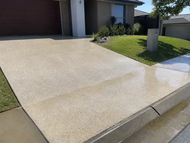 Freshly pressure-cleaned Brisbane driveway and front path with clean wet concrete after the job is finished