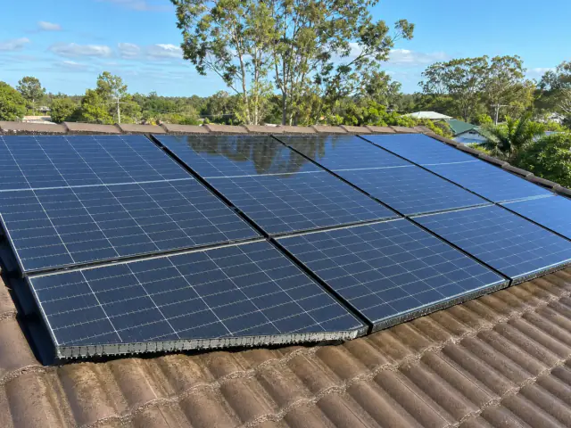 Freshly cleaned rooftop solar panels on a Brisbane home with clear glass and water beads after rinsing