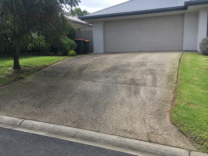 Same Brisbane exposed-aggregate driveway before pressure cleaning, with grime and algae staining