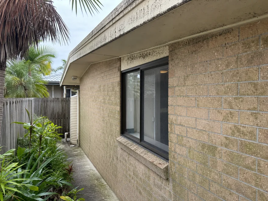 Same low-set Brisbane brick home before soft washing, with mould on the eaves and brickwork