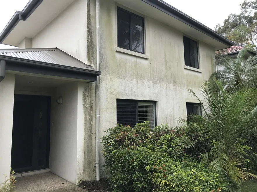 Same two-storey rendered Brisbane home before soft washing, with mould and algae staining